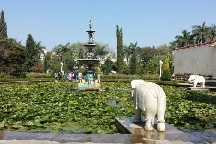Üppiger Garten mit einem mehrstufigen Brunnen und Elefantenstatuen aus weißem Marmor